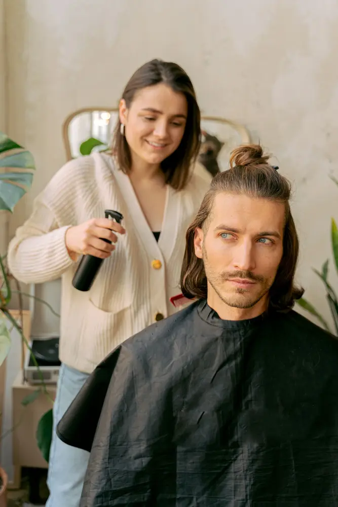 A stylist working with a client in a bright salon with green plants