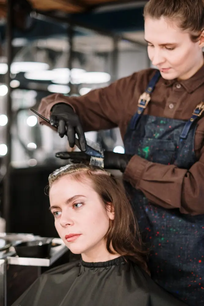 A hairstylist applying colour to a client's hair in a salon